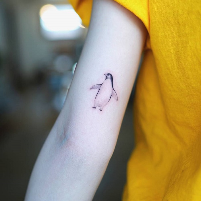 Minimalistic style penguin tattooed on the tricep.